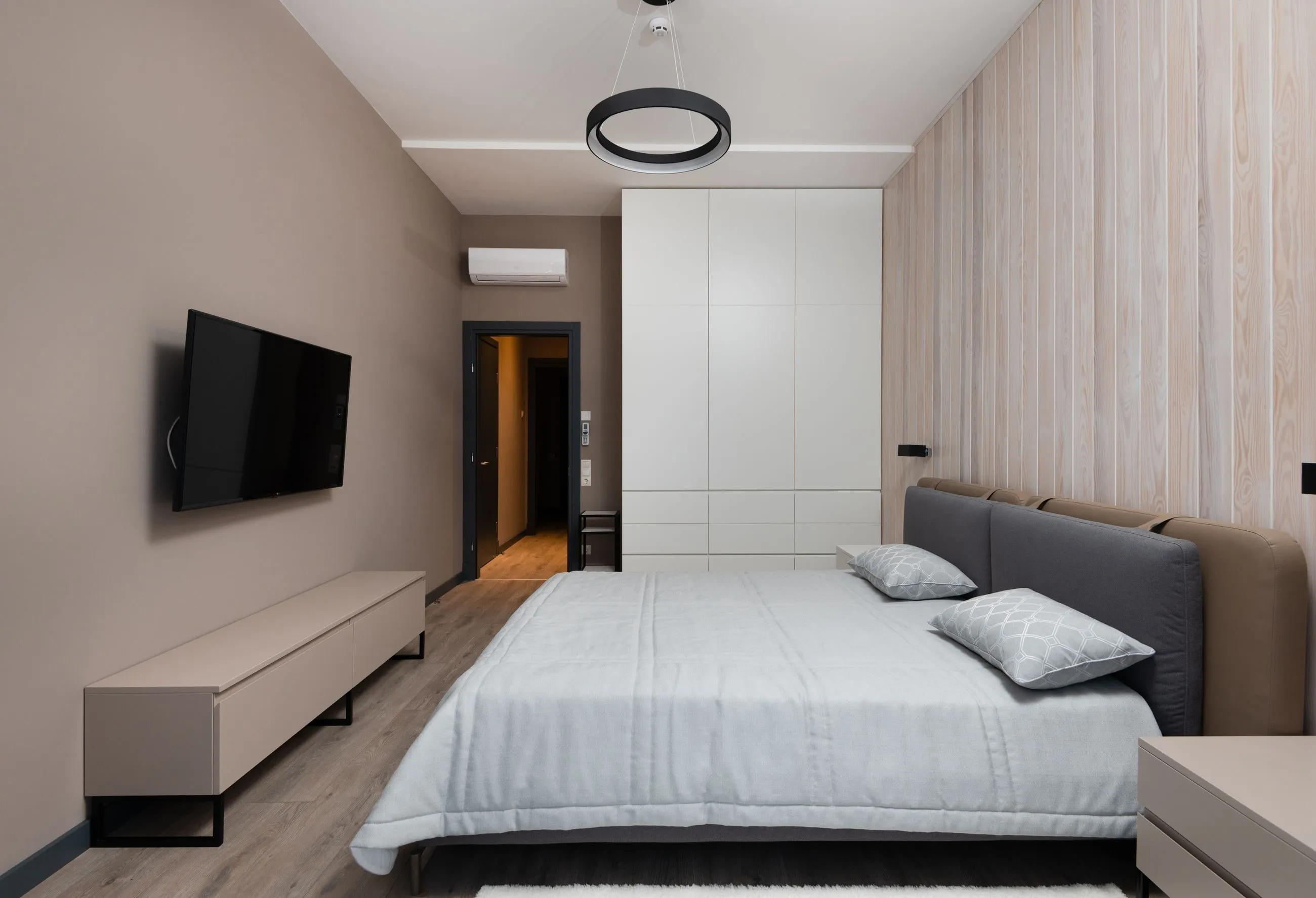 Dormitorio sobrio con cama tapizada y suelo de madera